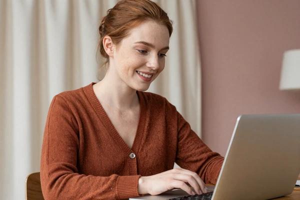 Smiling woman chatting from a cozy home desk, representing the small penis chat experience